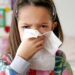 Ein Kind putzt sich die Nase mit einem Taschentuch.