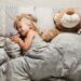 Schlafendes Mädchen mit verzerrtem Gesichtsausdruck im Bett