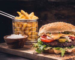 Ein Burger mit Pommes auf einem Holzbrett