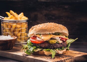 Ein Burger mit Pommes auf einem Holzbrett