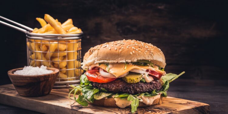 Ein Burger mit Pommes auf einem Holzbrett