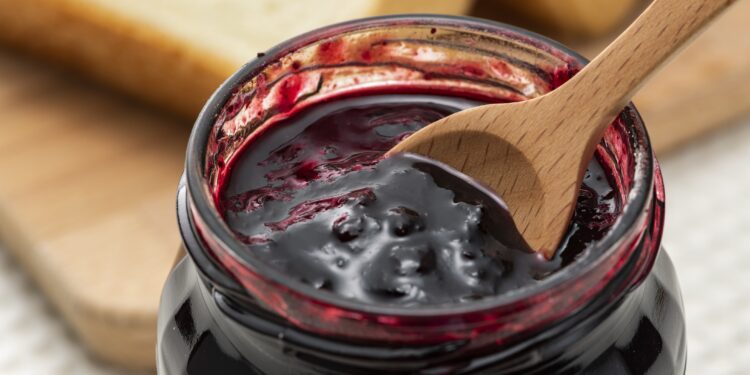 Ein Holzlöffel in einem Glas mit konservierten Heidelbeeren