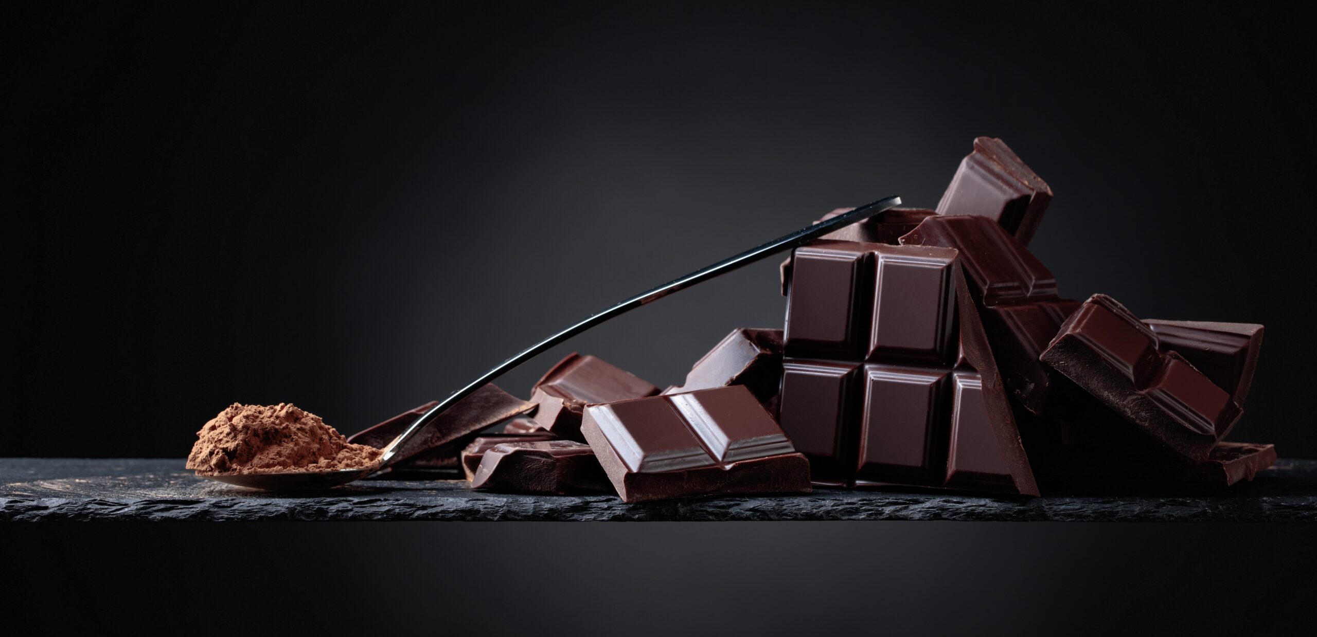 Тема шоколад. Шоколад на черном фоне. Фон темный шоколад. Плитка шоколада. Черный шоколад.