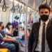 Junger Mann mit Anzug trägt in der U-Bahn eine Mund-Nasen-Bedeckung