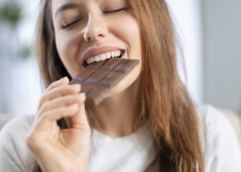 Eine Frau beißt genussvoll in eine Tafel Schokolade.