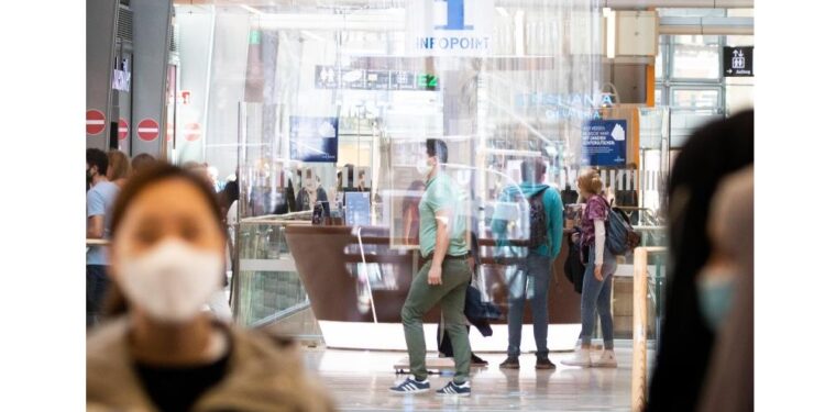 Menschen mit Mundschutz in einem öffentlichen Gebäude.