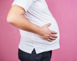 Ein Mann fasst sich an seinen dicken Bierbauch