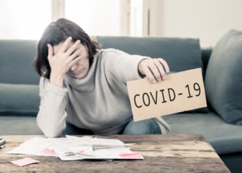 Eine Frau hält ein Schild mit der Aufschrift "COVID-19" hoch.