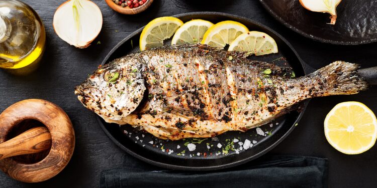 Gegrillter Fisch auf einem Teller mit Zitronenscheiben