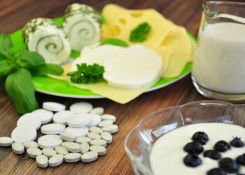 Kalziumreiche Lebensmittel wie Käse und Milch sowie Nahrungsergänzungsmittel auf einem Tisch