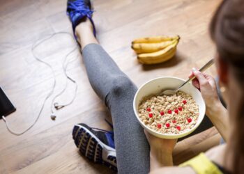 Eine Frau in Sportkleidung isst Müsli.