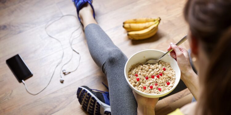 Eine Frau in Sportkleidung isst Müsli.