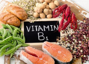 Eine Auswahl an Vitamin-B1-reichen Lebensmitteln um ein Schild mit der Aufschrift Vitamin B1