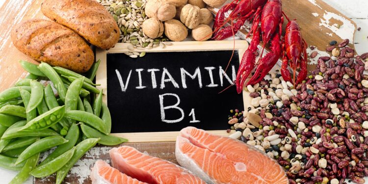 Eine Auswahl an Vitamin-B1-reichen Lebensmitteln um ein Schild mit der Aufschrift Vitamin B1