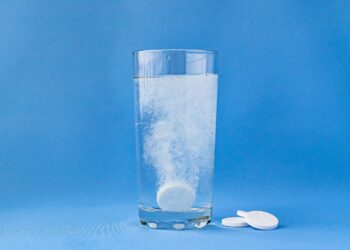 Eine Aspirin-Tablette löst sich in einem Glas mit Wasser auf.