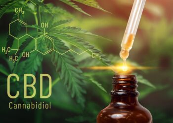 CBD-Tropfen mit Pflanze im Hintergrund