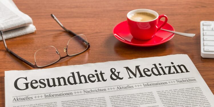 Auf einem Schreibtisch befinden sich eine Brille, eine Zeitung und eine Tasse Kaffee.