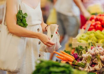 Eine Frau packt auf einem Markt Obst und Gemüse in einen Beutel