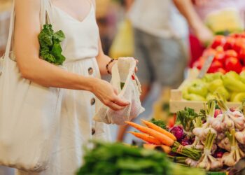 Eine Frau packt auf einem Markt Obst und Gemüse in einen Beutel