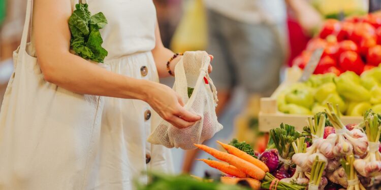 Eine Frau packt auf einem Markt Obst und Gemüse in einen Beutel