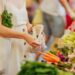 Eine Frau packt auf einem Markt Obst und Gemüse in einen Beutel