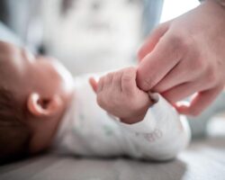 Ein Baby greift die Hand eines Erwachsenen.