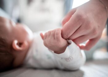 Ein Baby greift die Hand eines Erwachsenen.