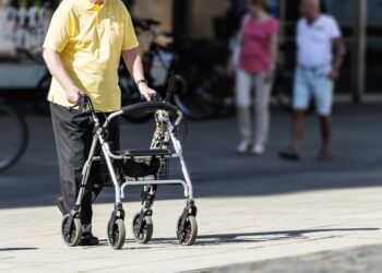 Alter Frau mit Rollator als Gehhilfe.