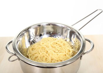 Gekochte Spaghetti in einem Metallsieb in einem Topf