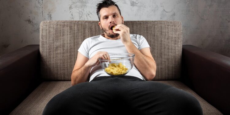 Mann vor dem Fernseher auf Sofa mit Chips.