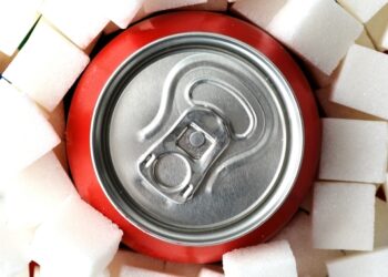 Eine rote Softdrink-Dose inmitten von Würfelzucker