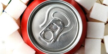 Eine rote Softdrink-Dose inmitten von Würfelzucker