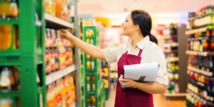 Eine Angestellte im Supermarkt kontrolliert die Getränke.