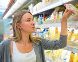 Eine Frau nimmt ein Käse-Produkt aus einem Kühlregal in einem Supermarkt.