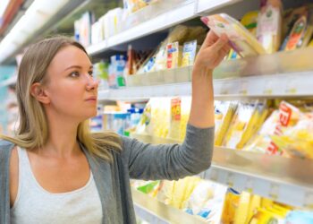 Eine Frau nimmt ein Käse-Produkt aus einem Kühlregal in einem Supermarkt.