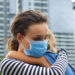 Mutter mit Mundschutz umarmt ihr Kind