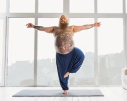Mann steht auf einem Bein und macht Yoga.