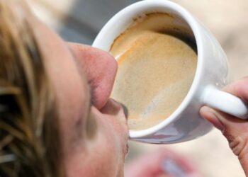 Eine Person nimmt einen Schluck Kaffee aus einer Tasse.