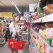 Eine junge Frau nimmt eine Packung Chips aus einem Regal im Supermarkt.
