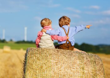 Zwei kleien Jungen sitzen auf einem Heuhaufen