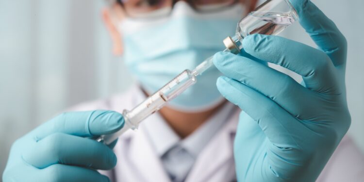Mediziner mit einer Spritze und einer Impfstoffampulle