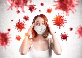Frau mit Maske schaut ängstlich auf Viren.