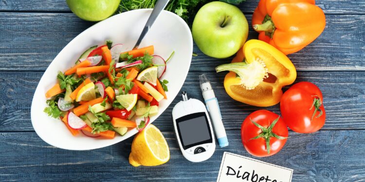 Digital blood glucose meter, lancet pen and a bowl of salad on a table