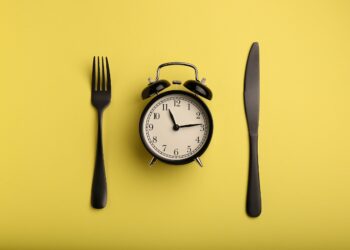 Eine Gabel, ein Wecker und ein Messer auf gelbem Hintergrund