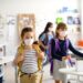 Mehrere Kinder mit Mund-Nasen-Bedeckung in einem Klassenzimmer