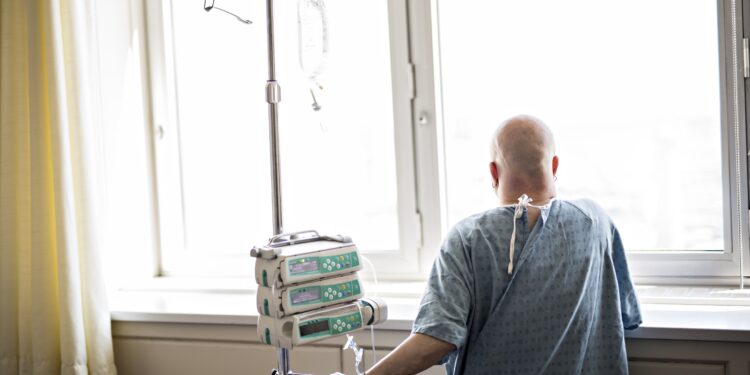 Krebspatientin ohne Haare sieht aus dem Fenster eines Krankenhauszimmers