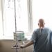 Krebspatientin ohne Haare sieht aus dem Fenster eines Krankenhauszimmers