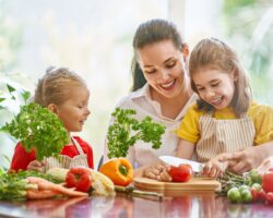 Kinder mit Mutter schneiden Obst und Gemüse.