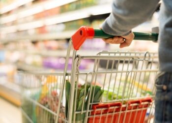 Mann mit einem vollen Einkaufswagen im Supermarkt