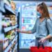 Junge Frau mit Mund-Nasen-Bedeckung beim Einkaufen im Supermarkt